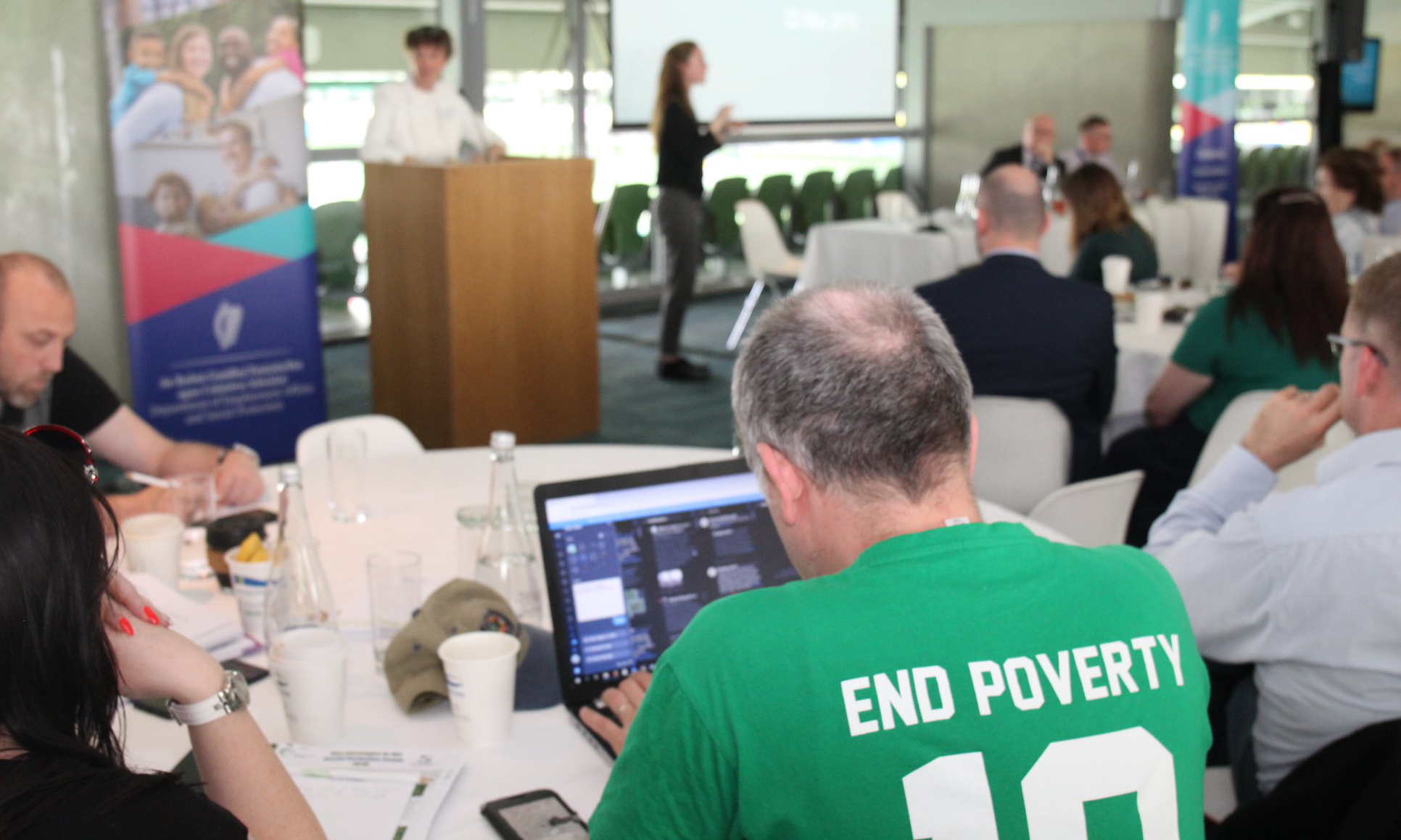 Man in SIF audience wears 'End Poverty' shirt